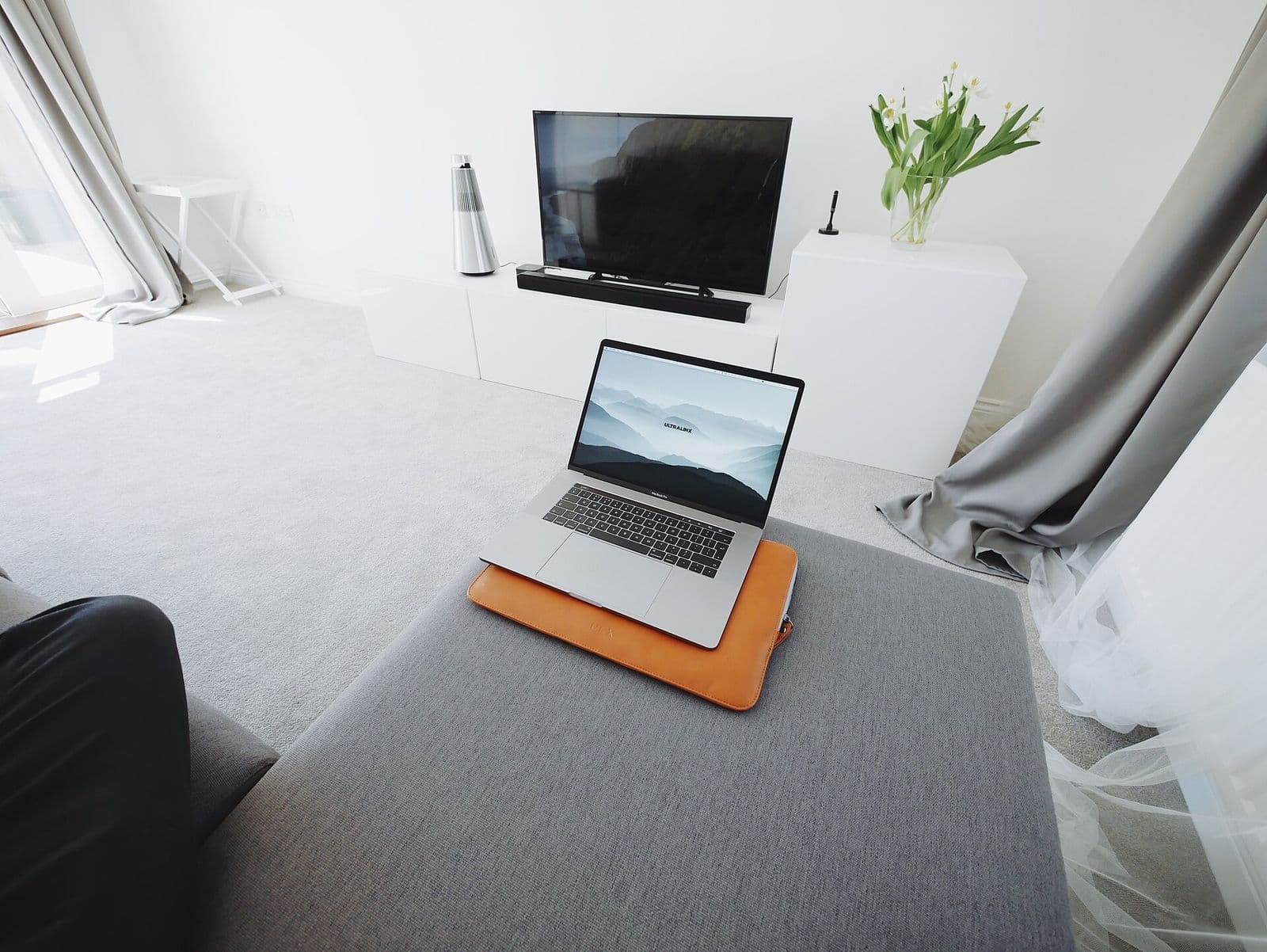 A bright modern living room with a wall-mounted TV and a laptop, a typical cord-cutting setup in an American home